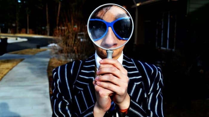 person using magnifying glass enlarging the appearance of his nose and sunglasses