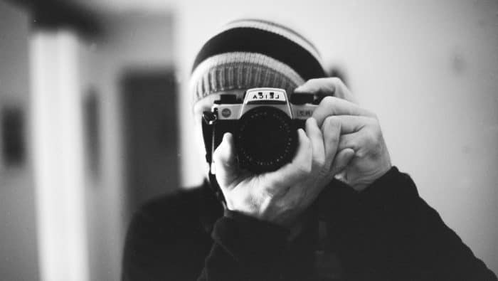 grayscale photo of person holding camera